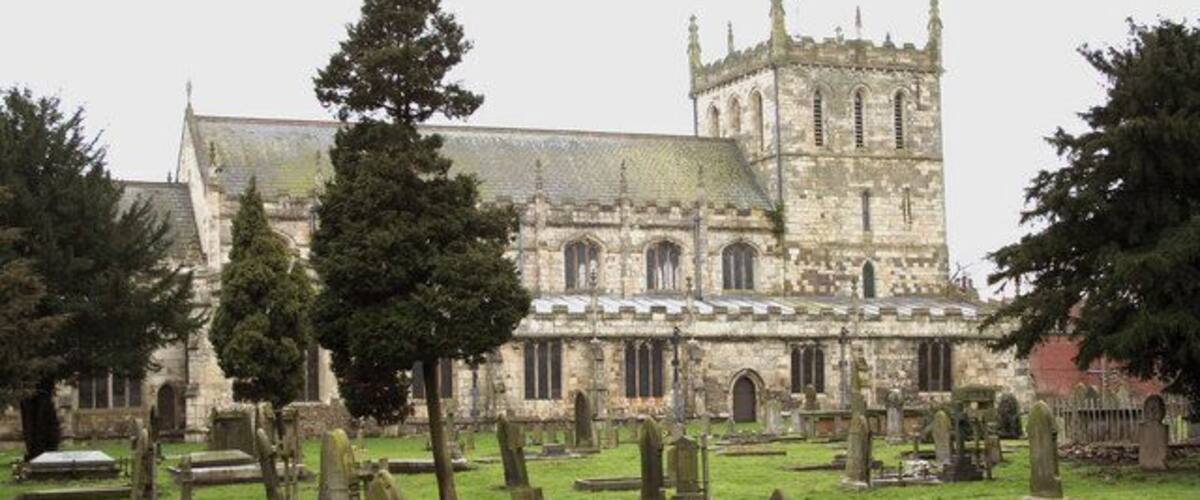 A historic church with a tall tower and a cemetery in front.