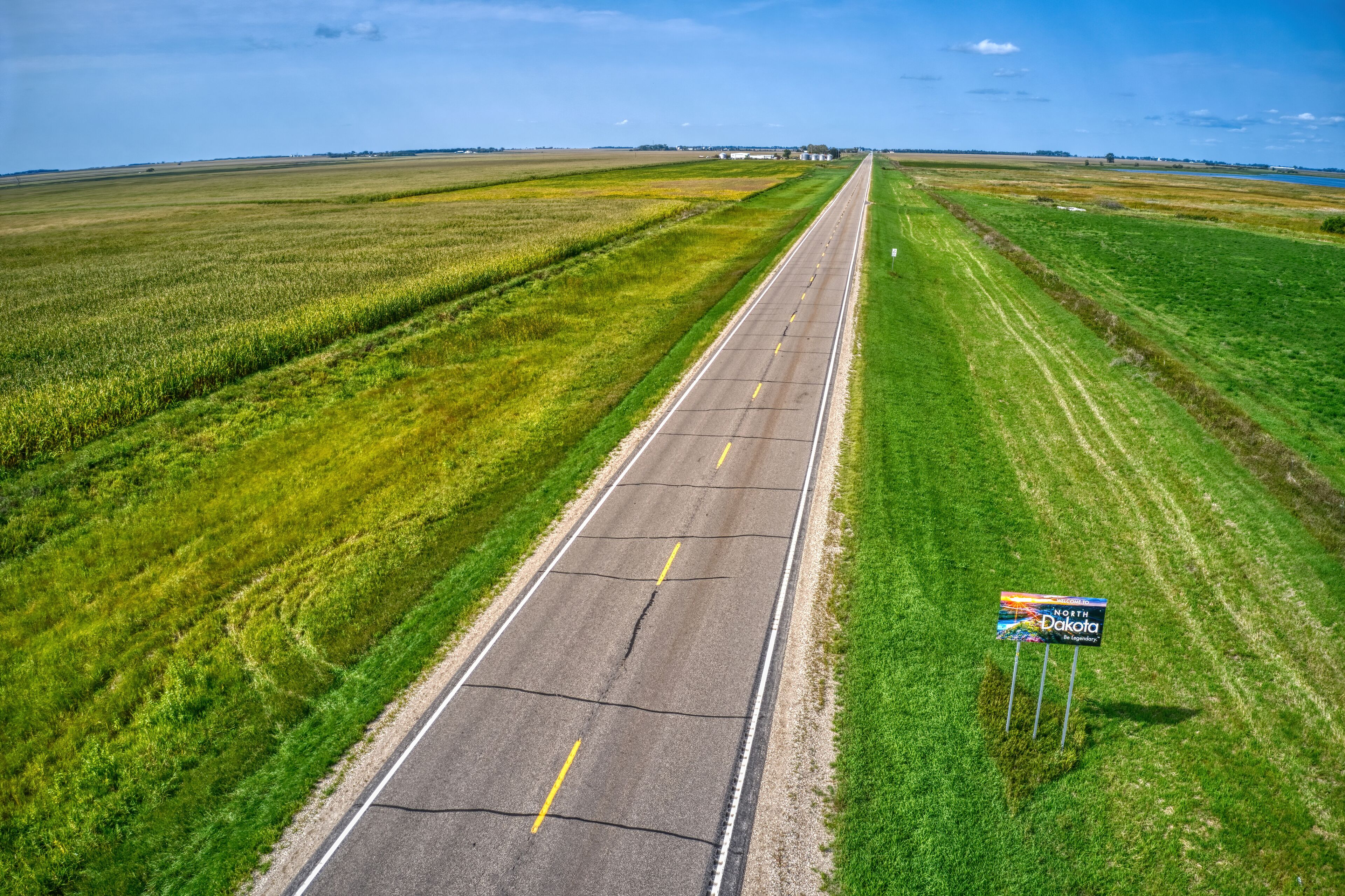 A straight road with a sign indicating North Dakota.