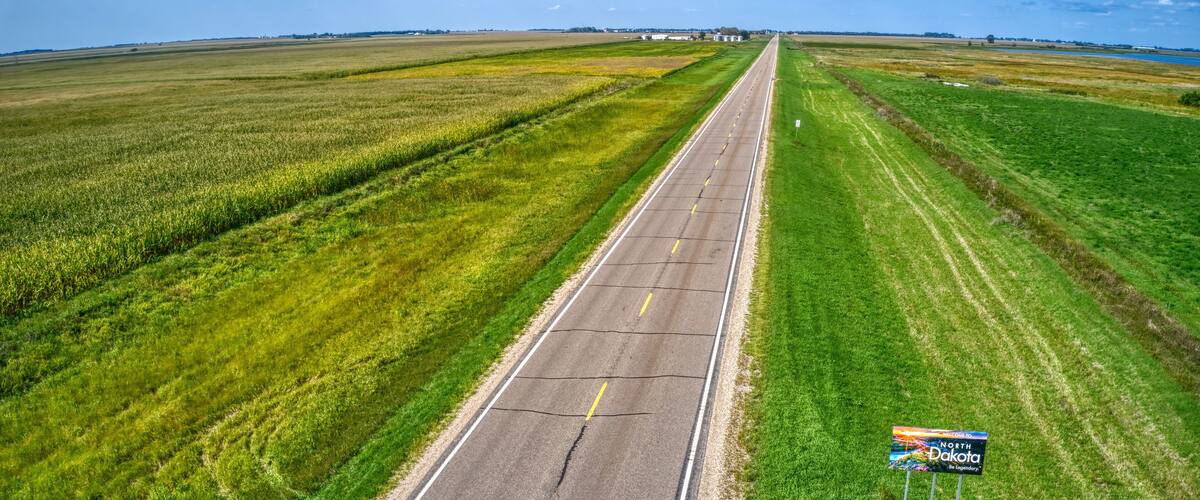A straight road with a sign indicating North Dakota.