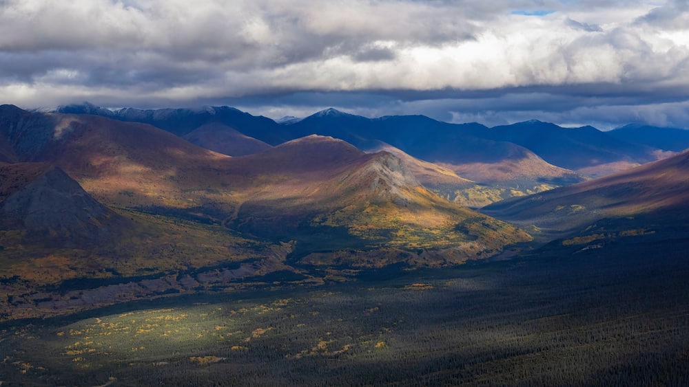 Stunning aerial view of the Ruby Range under heavy clouds near Destruction Bay, with autumn setting in on the Yukon landscape; Destruction Bay, Yukon, Canada