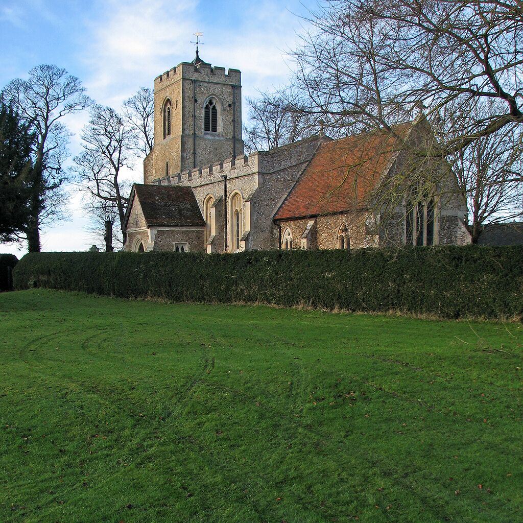 A church with a prominent tower and arched windows, surrounded by a well-maintained lawn and leafless trees.