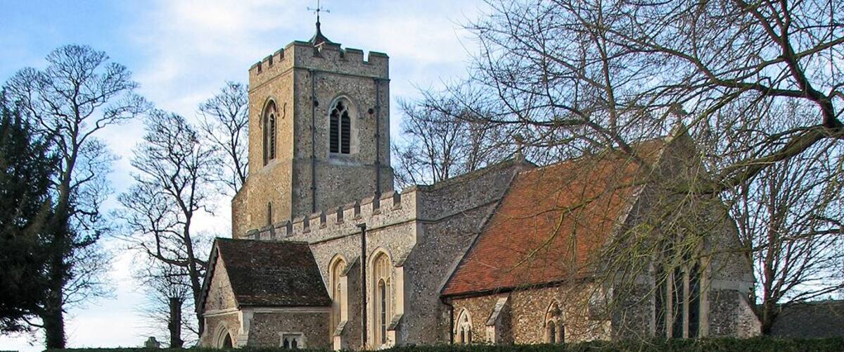 A church with a prominent tower and arched windows, surrounded by a well-maintained lawn and leafless trees.