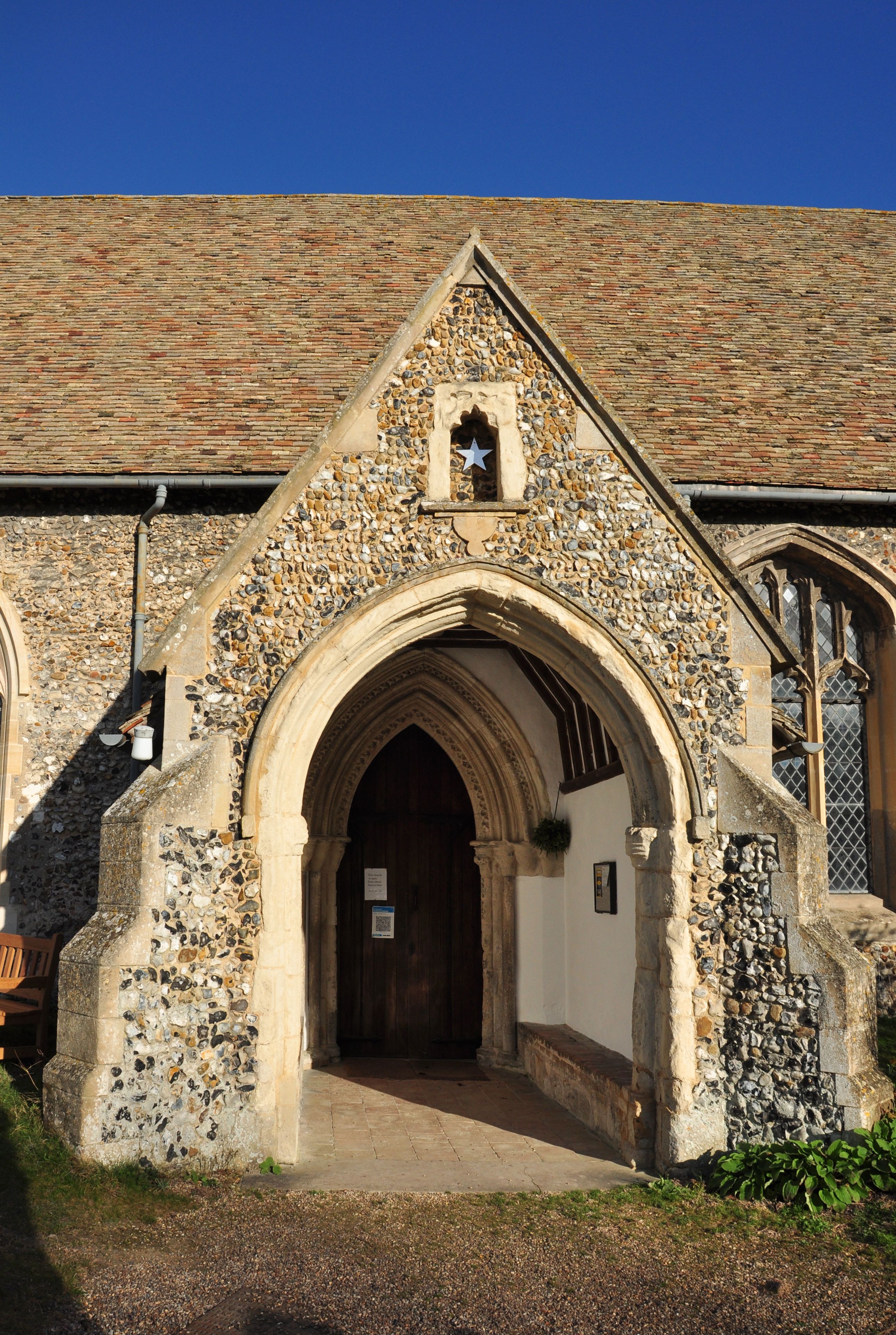 A stone church with a pointed arch entrance, a small bell tower, and a tiled roof.