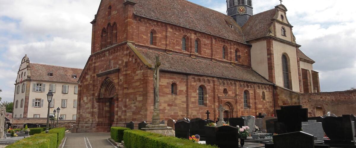 A historic church with a tall bell tower and a cemetery in front.