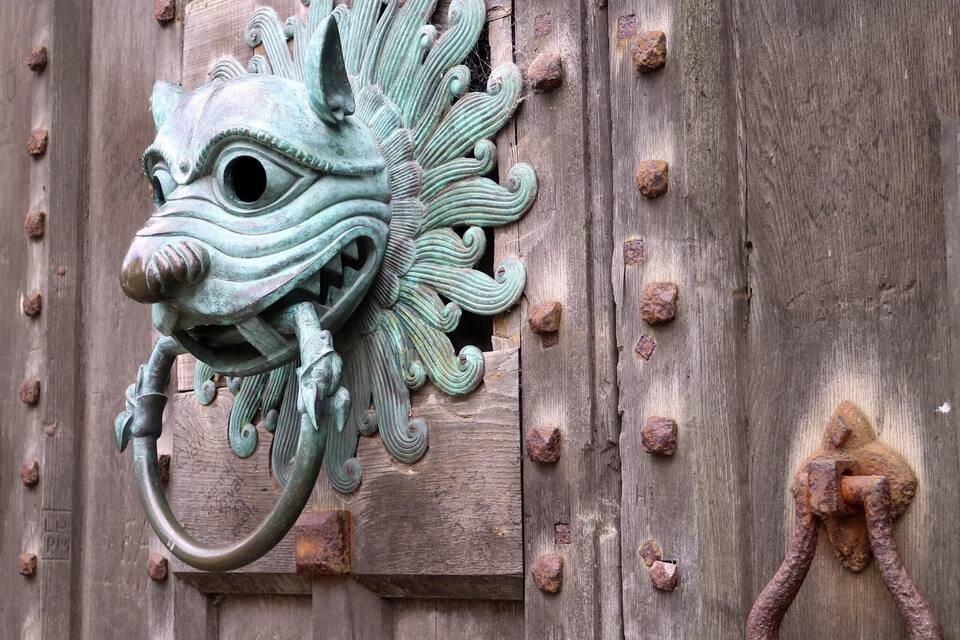 Un aldabilla de metal con diseño de cabeza de dragón.