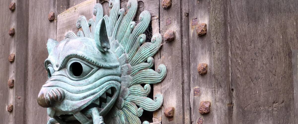A metal door knocker with a dragon head design.