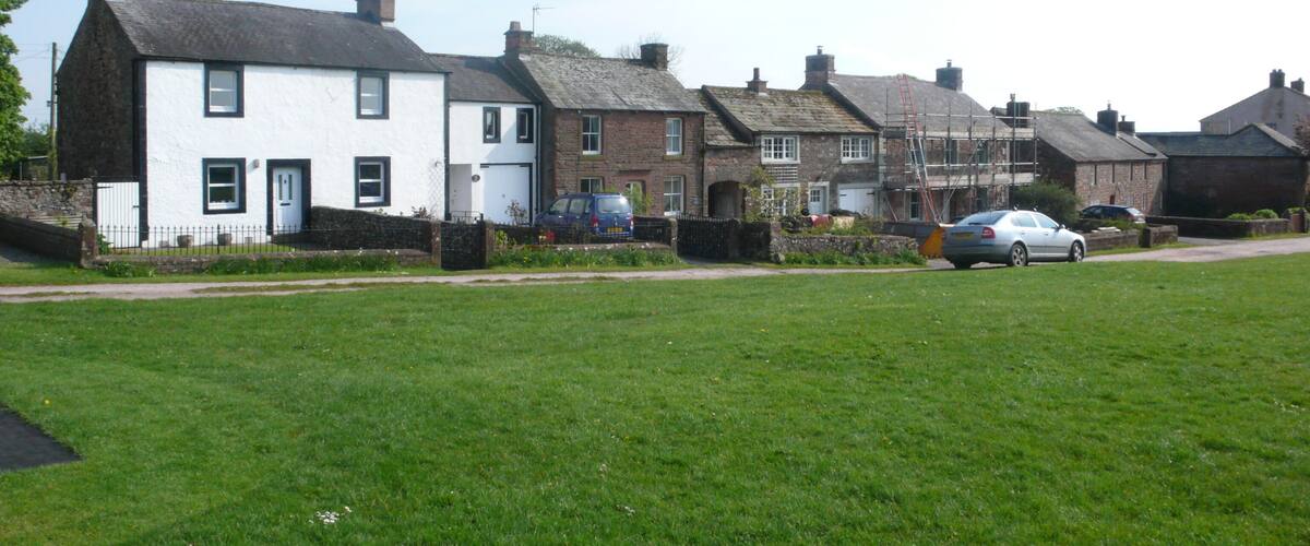 A row of white and brick houses with a grassy field in the foreground.
