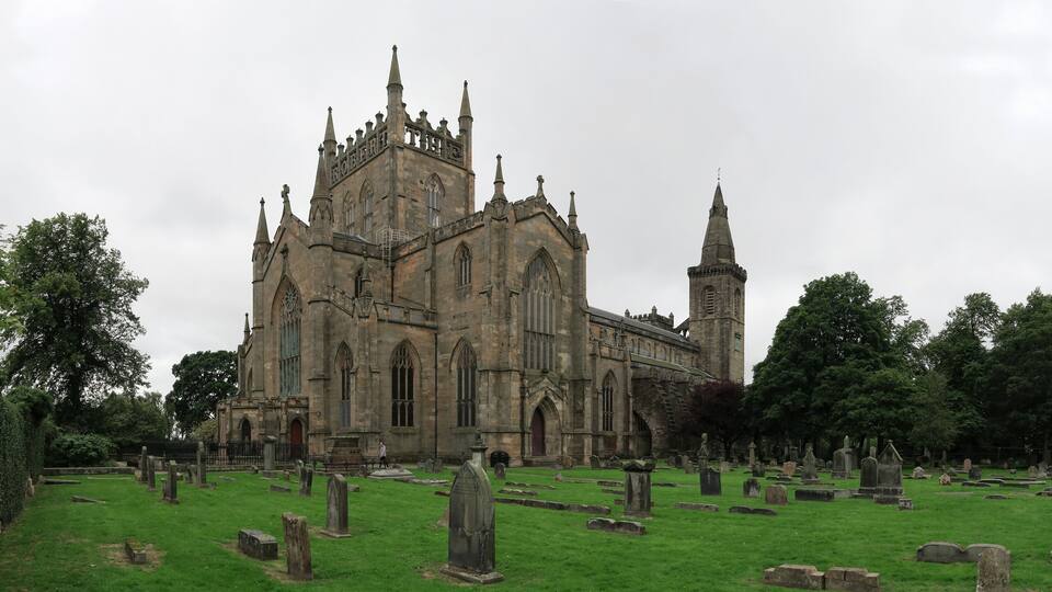 A Gothic-style church with a tall tower and a cemetery in front.