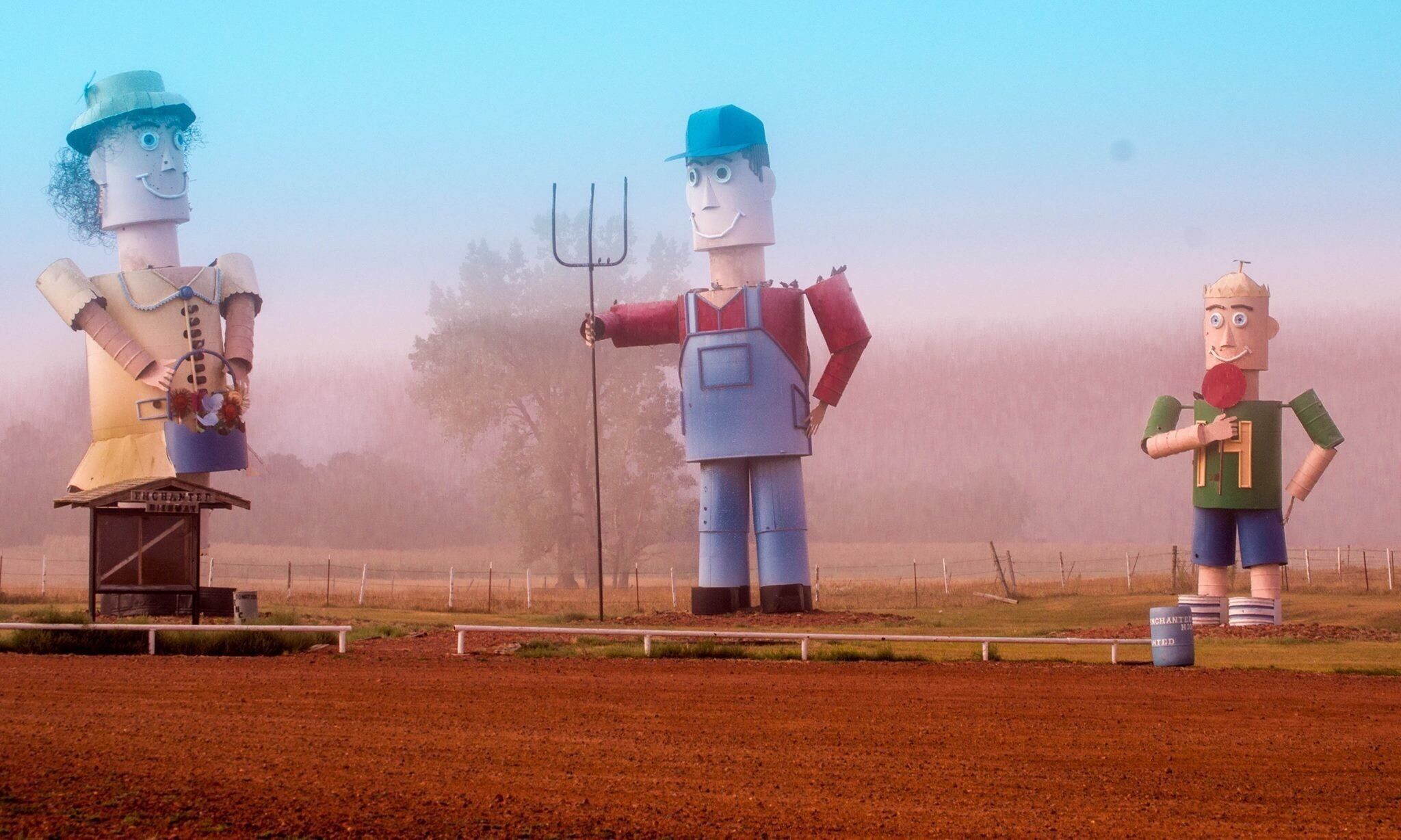 Three large, colorful sculptures in a field.