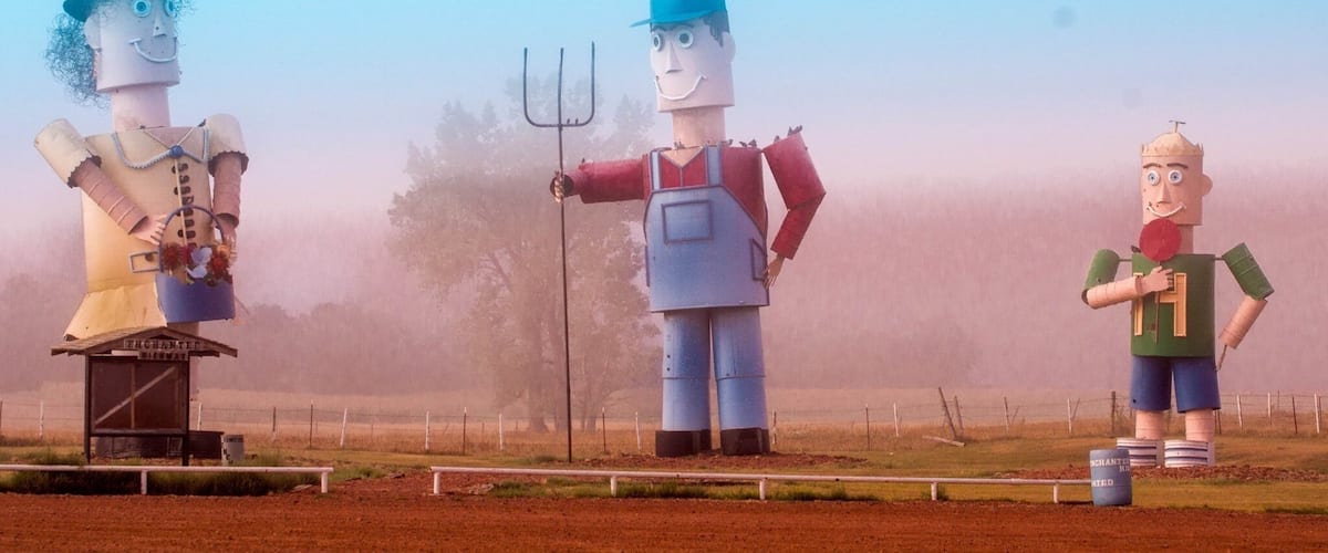 Three large, colorful sculptures in a field.