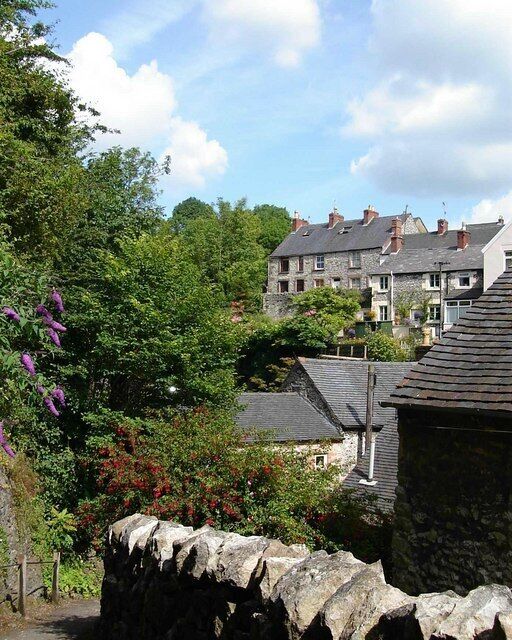 A stone wall, a stone building, and a house with a grey roof.