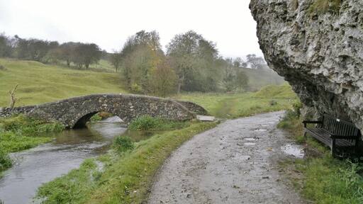 Harold Gee's bench beneath the rock overlooking the packhorse bridge over the River Bradford near Bradford, near Youlgreave, Derbyshire