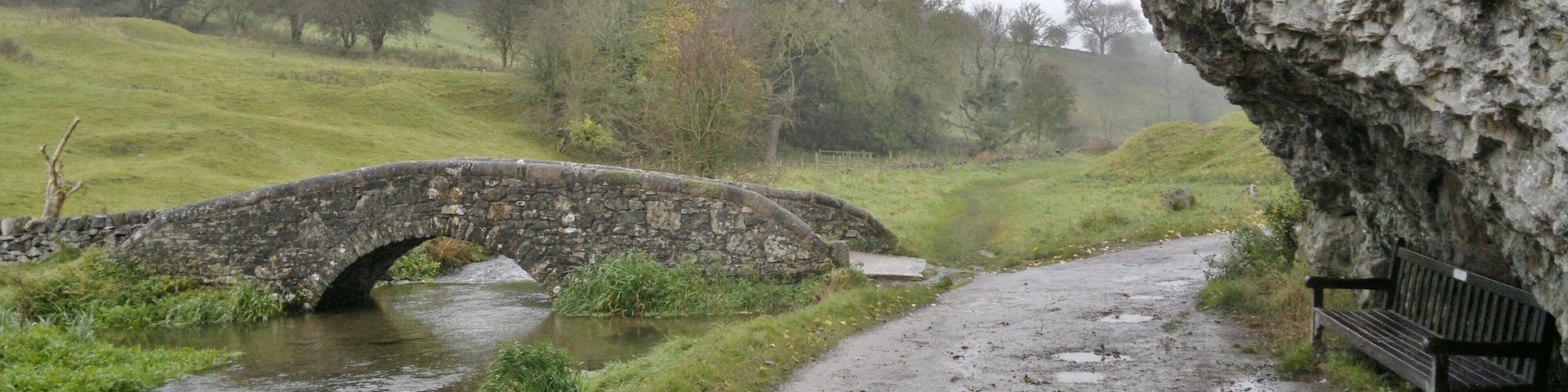 Harold Gee's bench beneath the rock overlooking the packhorse bridge over the River Bradford near Bradford, near Youlgreave, Derbyshire