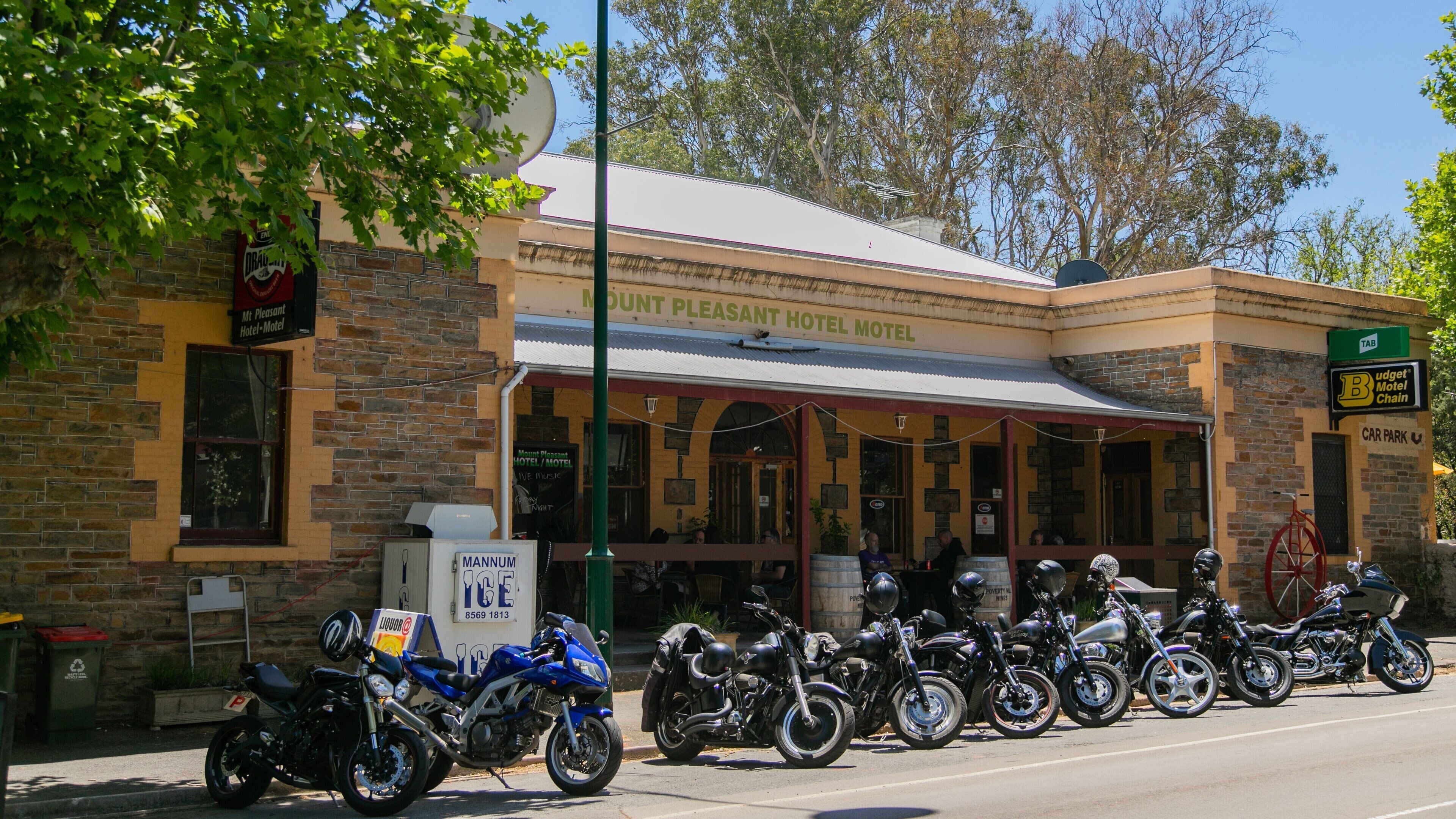 A building with a sign that reads "Mt Pleasant Hotel Motel." There are motorcycles parked in front of the building.