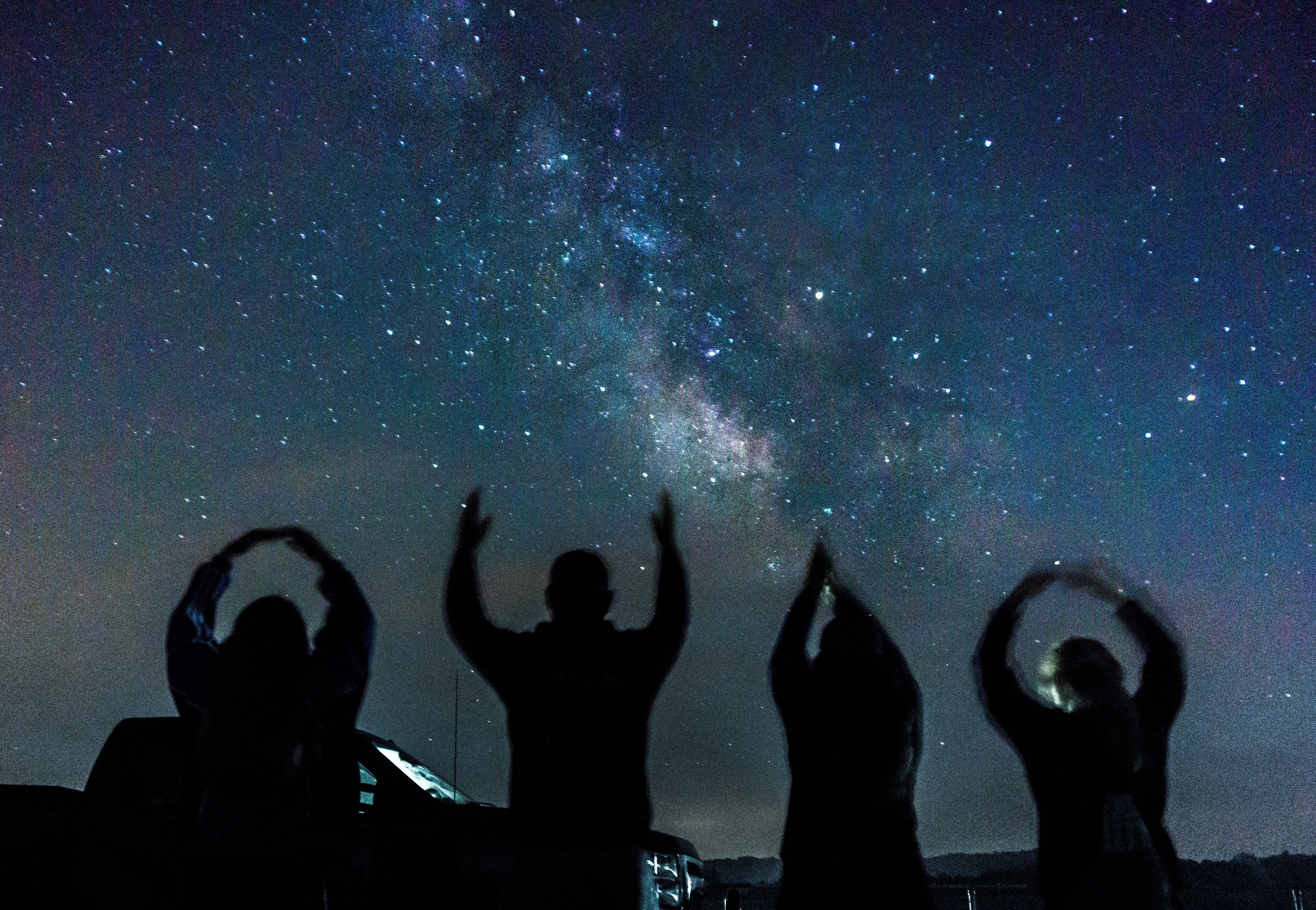 Silhouettes of people against a starry night sky.