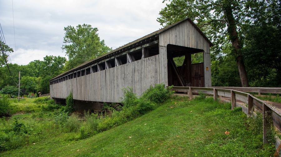 A wooden covered bridge in a lush, green landscape.
