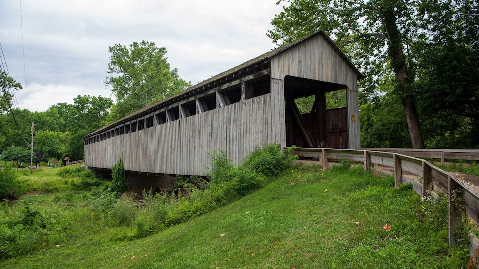 A wooden covered bridge in a lush, green landscape.