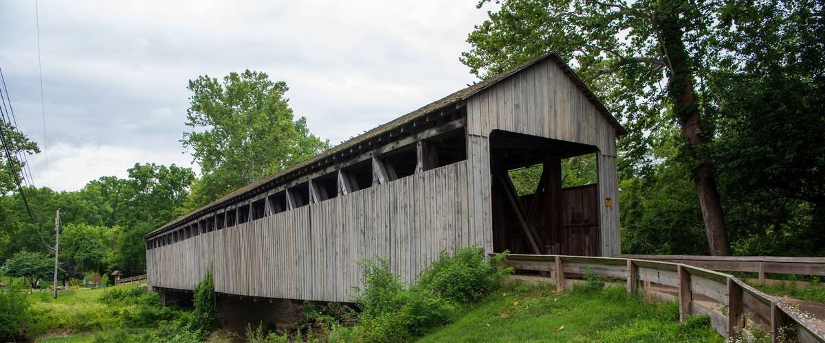 A wooden covered bridge in a lush, green landscape.
