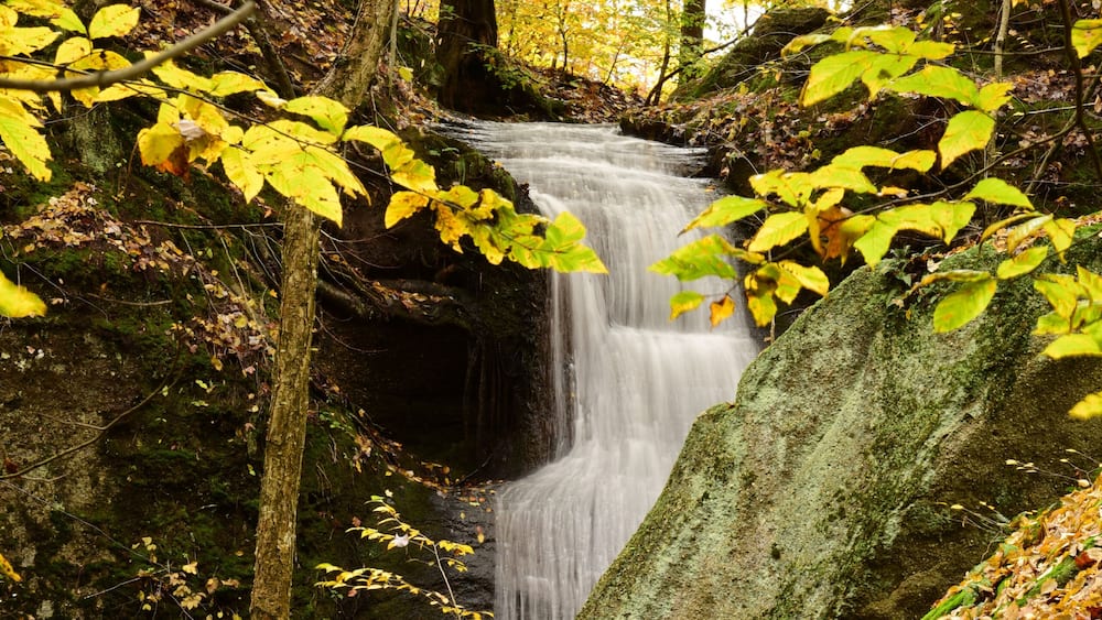 Cascade Falls among leaves and moss covered boulders in Nelson Ledges State Park on a beautiful Autumn day