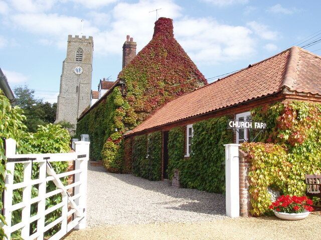 Church Farm, Hindringham, Norfolk, seen from the south, with the west tower of St Martin's parish church in the background