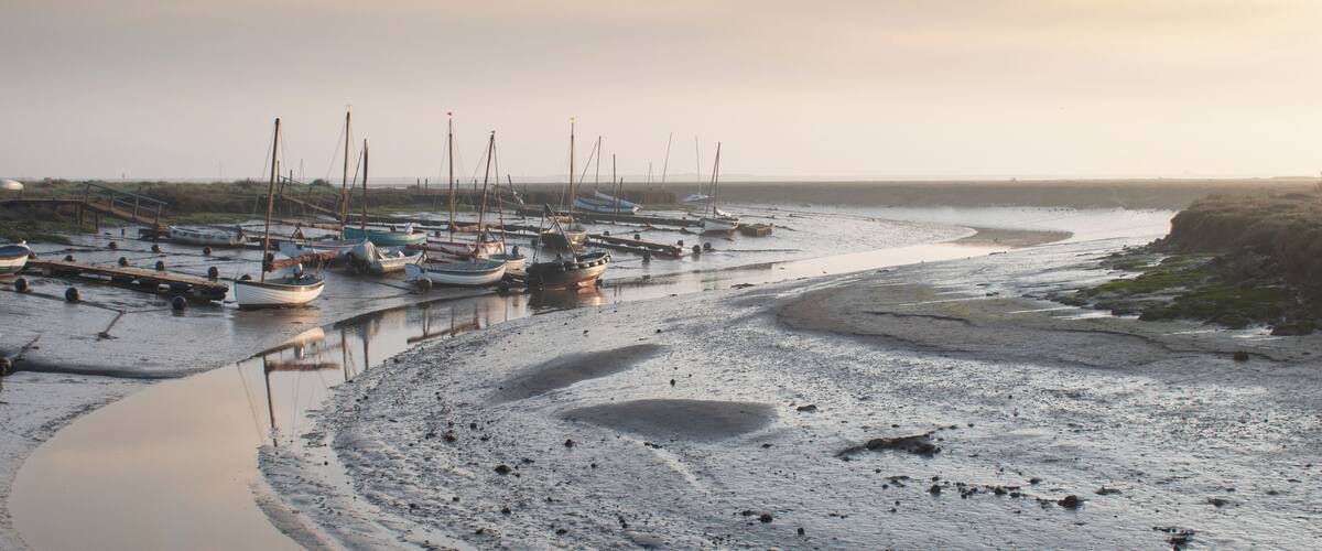 A coastal marina with boats docked along a sandy shore.