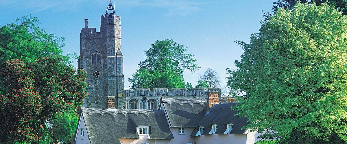 A historic building with a tower and a thatched-roof house.