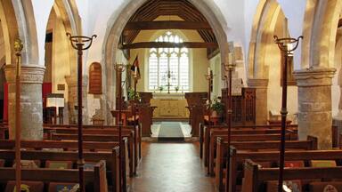 An interior of a church with arched ceilings, wooden pews, and stained glass windows.