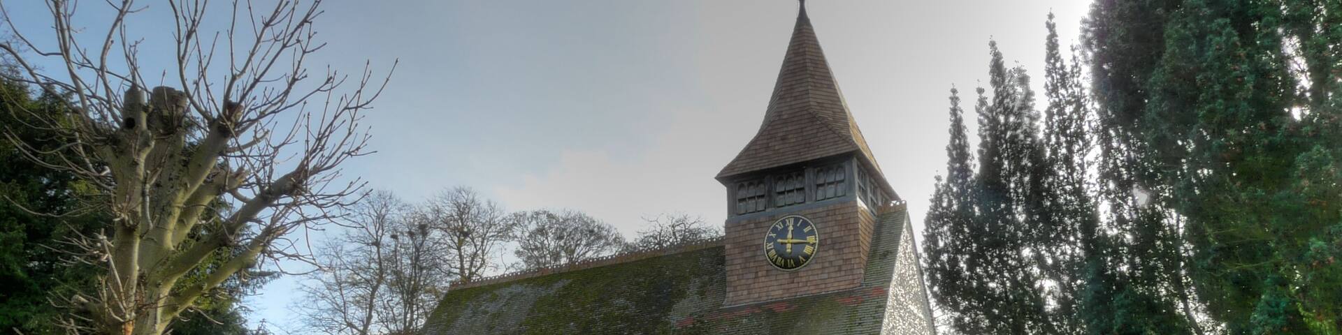 A church with a clock tower, surrounded by a cemetery with gravestones.