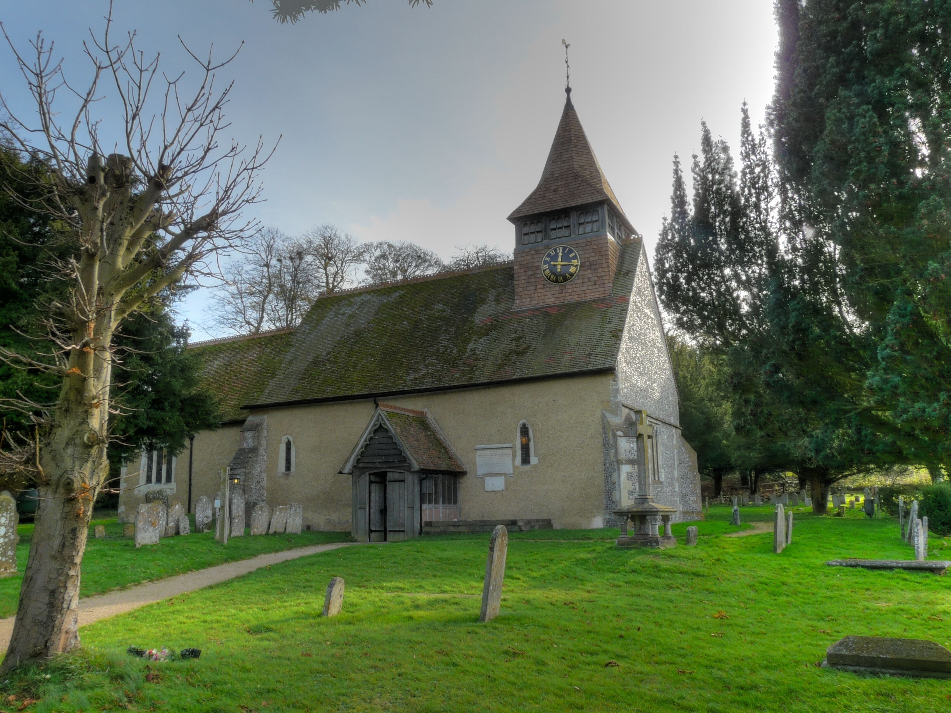 A church with a clock tower, surrounded by a cemetery with gravestones.