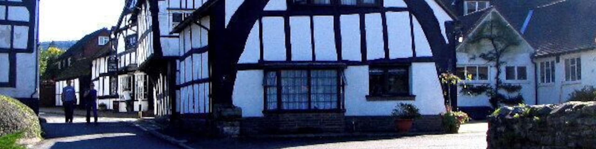 Un edificio de estilo Tudor tradicional, con un tejado empinado y estructura de entramado de madera en blanco y negro.