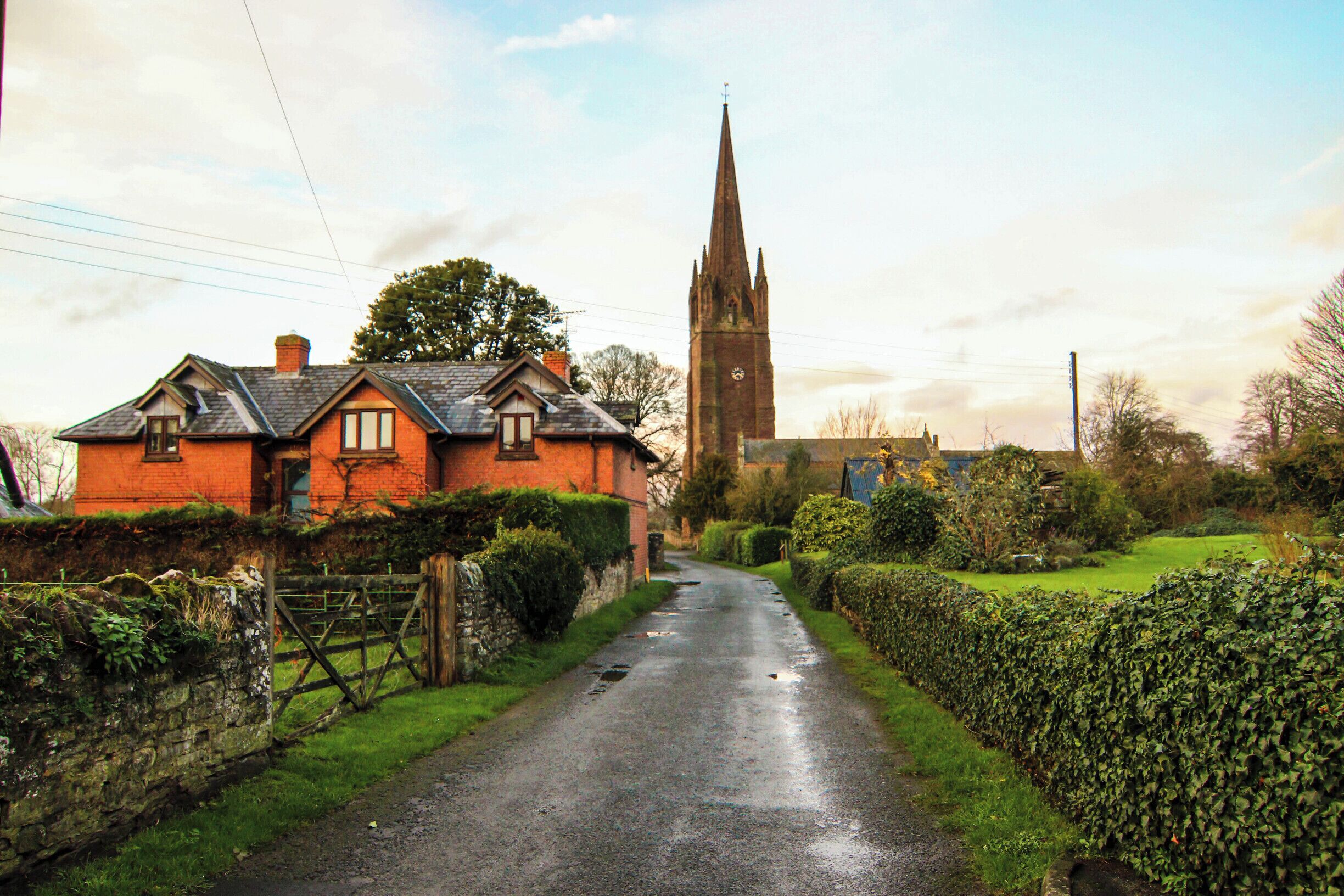 A rural road with a church and a red brick house.