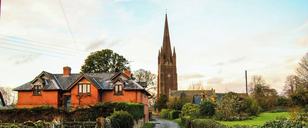 A rural road with a church and a red brick house.