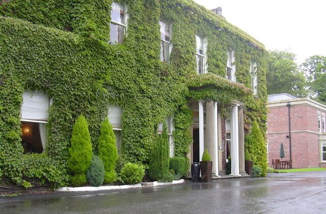 A building covered in ivy, with a white facade and columns at the entrance.
