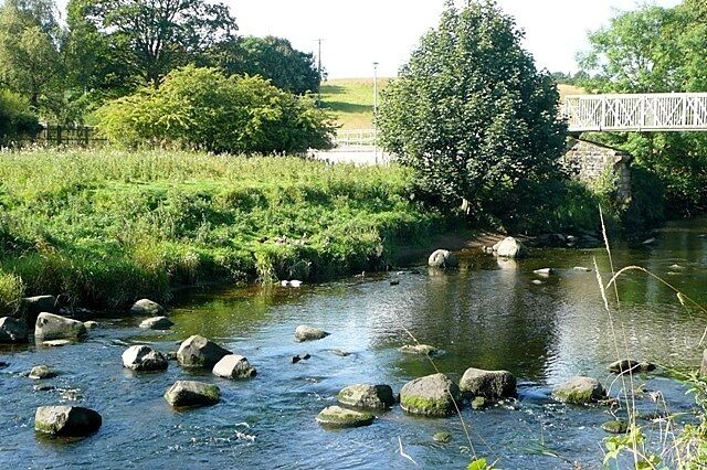 A river with rocks, a bridge, and greenery.
