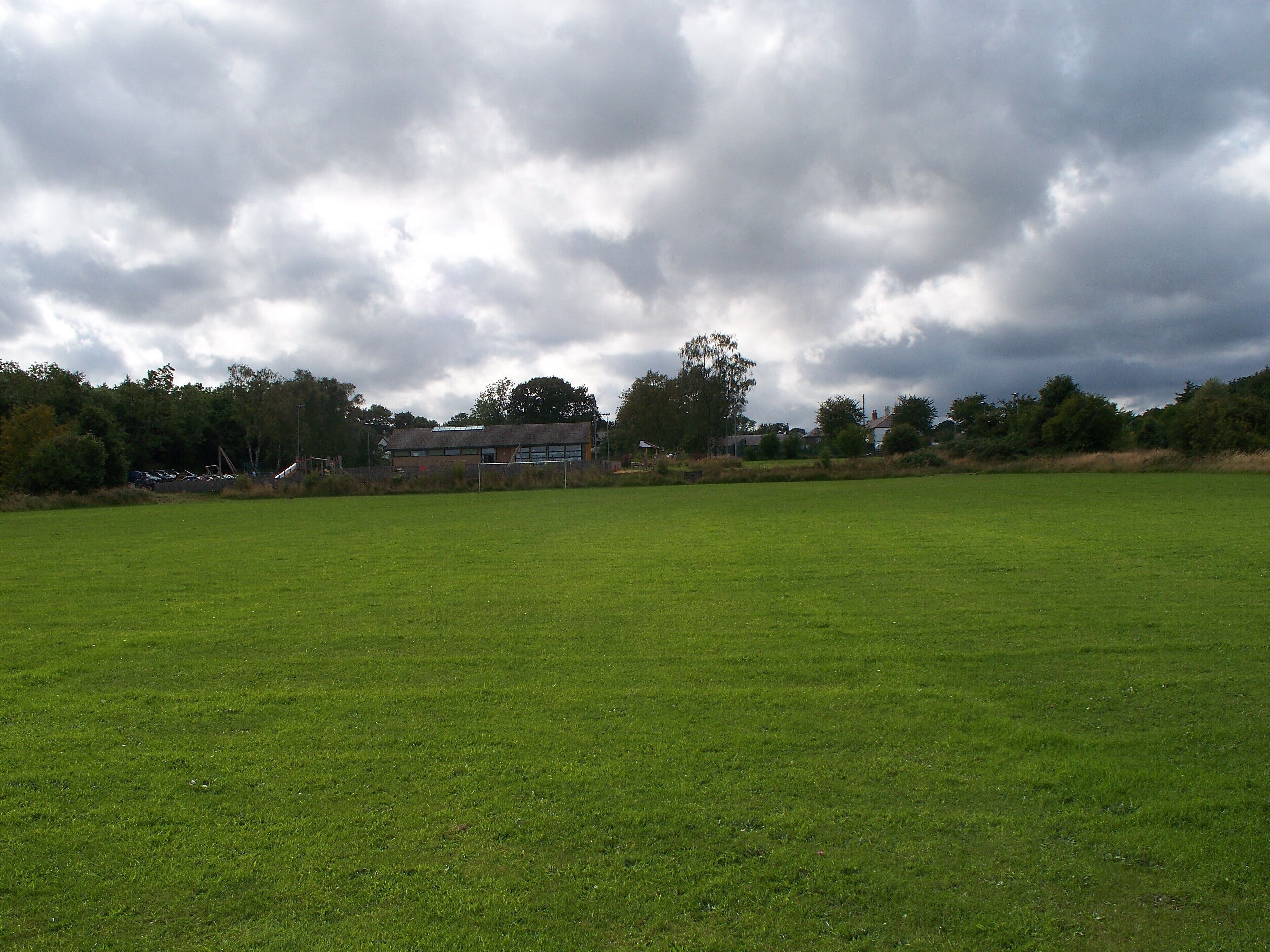 A large green field with a building in the background.