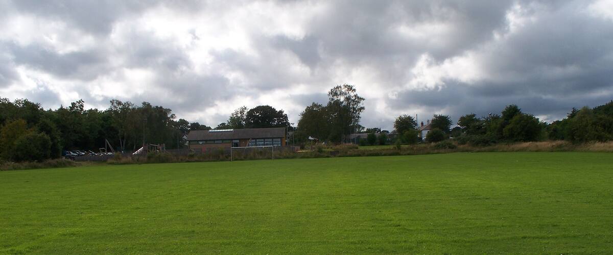 A large green field with a building in the background.