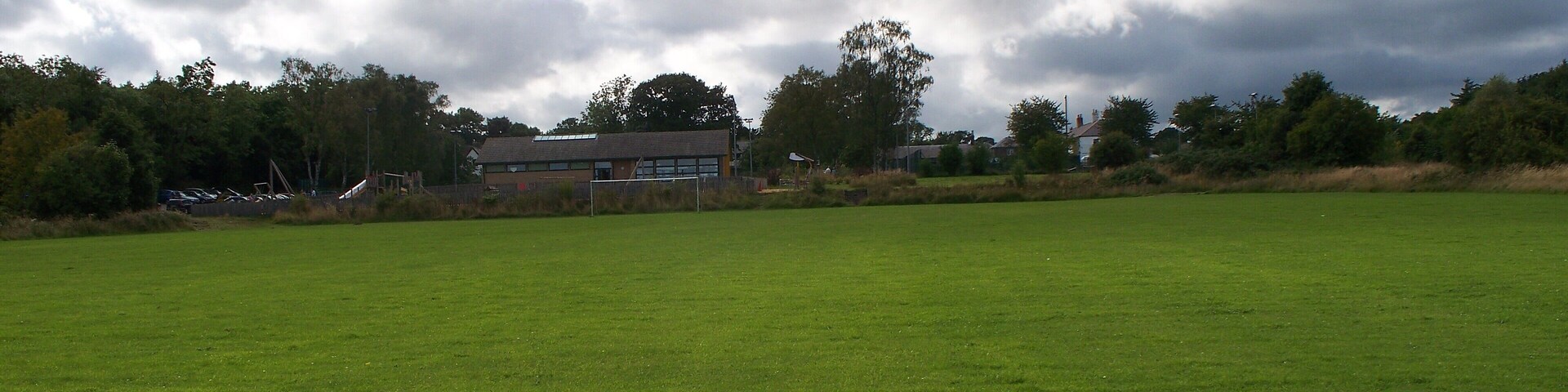 A large green field with a building in the background.