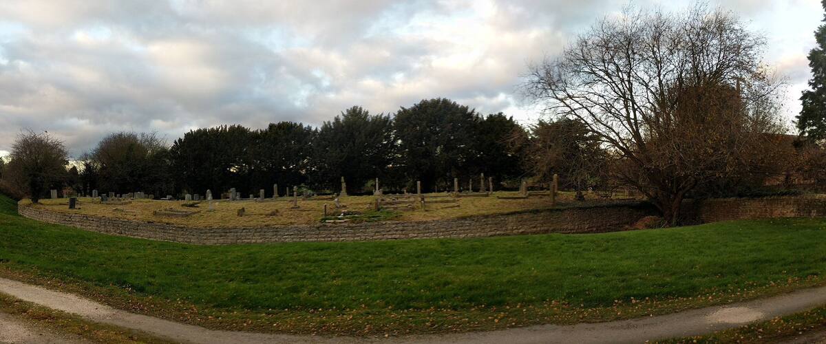 A cemetery with headstones and a path.