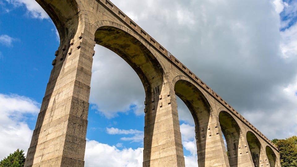 A large stone bridge with multiple arches under a partly cloudy sky.