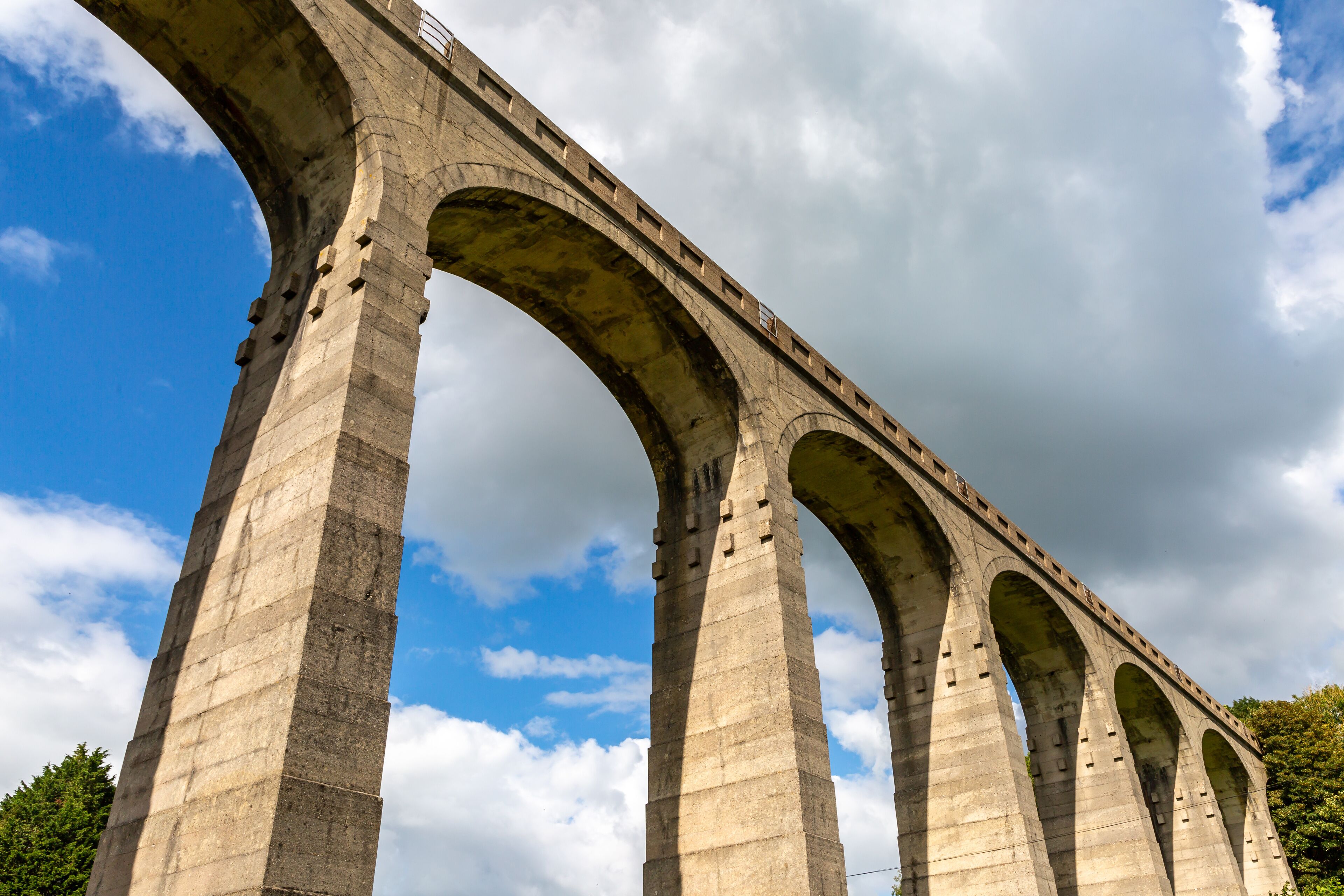 A large stone bridge with multiple arches under a partly cloudy sky.