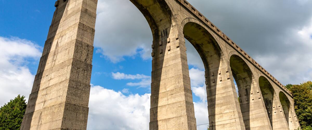 A large stone bridge with multiple arches under a partly cloudy sky.