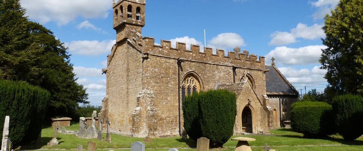 A historic church with a bell tower and a cemetery in front.