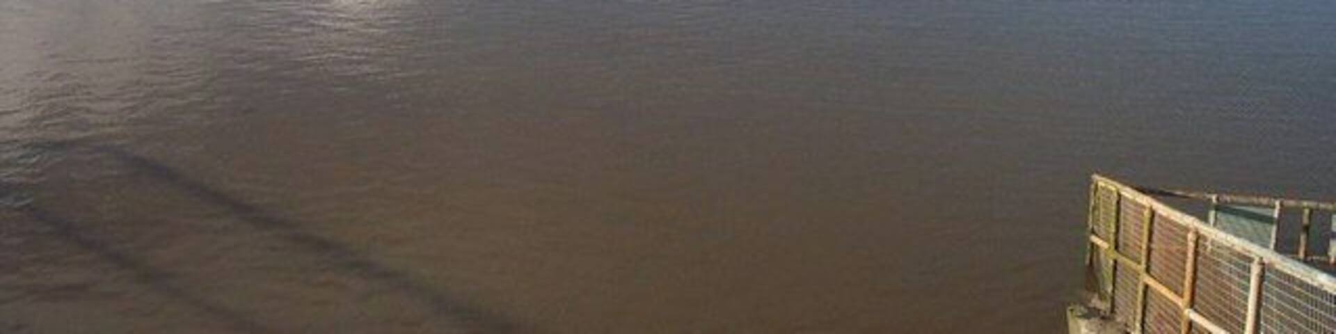 The Huntspill River where it enters the Parrett Estuary Taken from the sluice gate, with the estuary of the River Parrett in the middle distance.