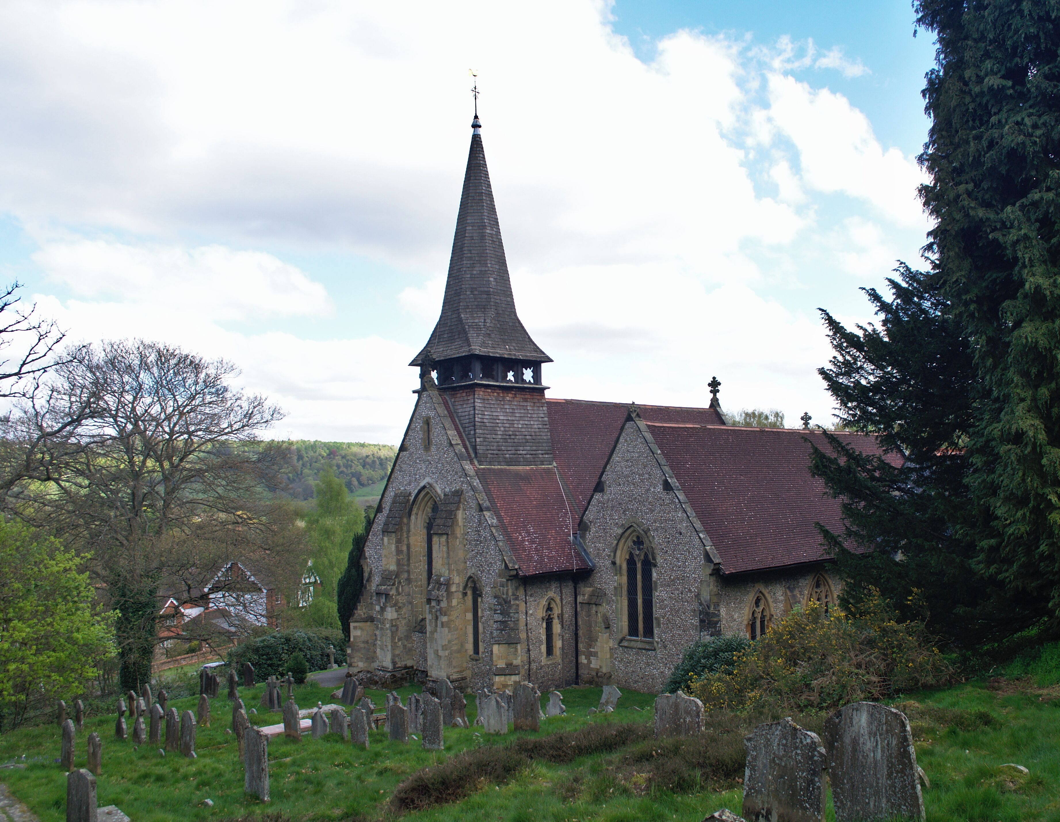 A church with a tall steeple and a graveyard in the foreground.
