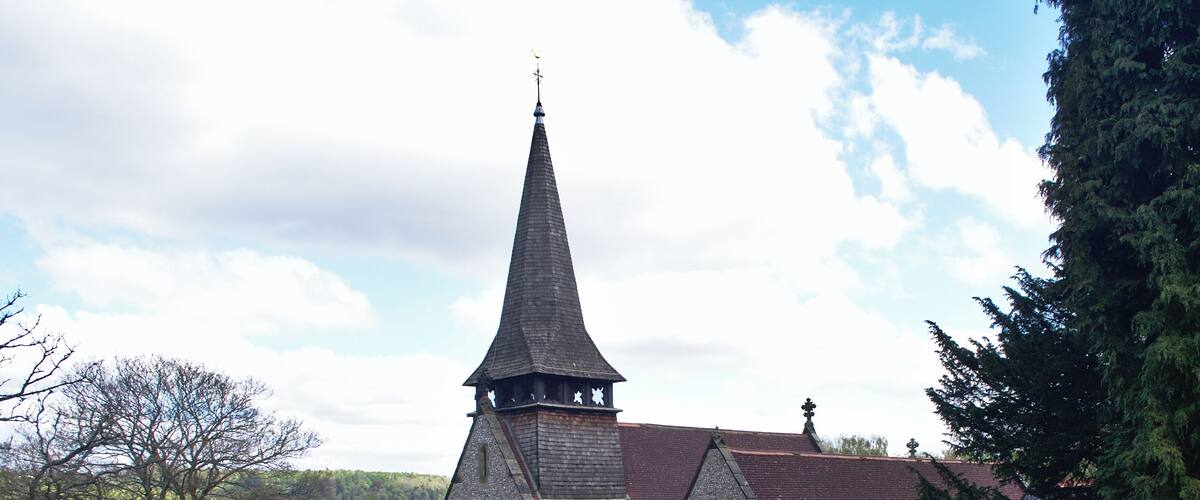 A church with a tall steeple and a graveyard in the foreground.