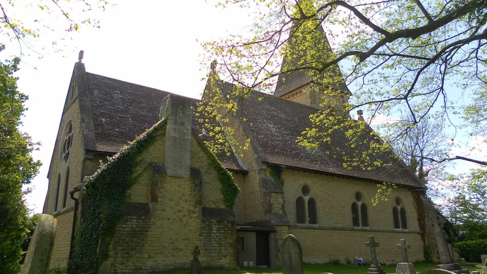 A church with a tall steeple and a graveyard in front.