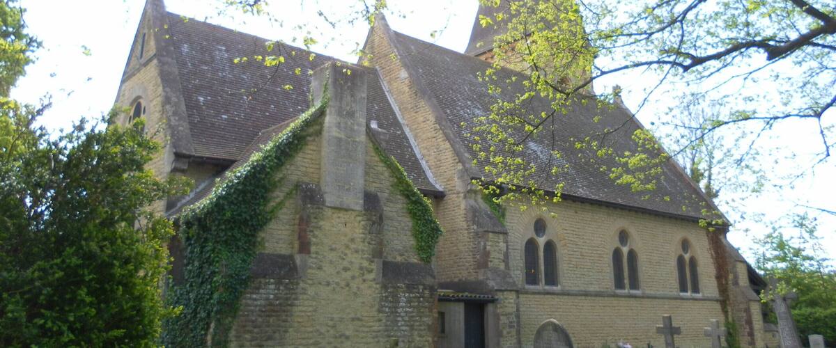 A church with a tall spire, ivy-covered walls, and a cemetery with headstones.