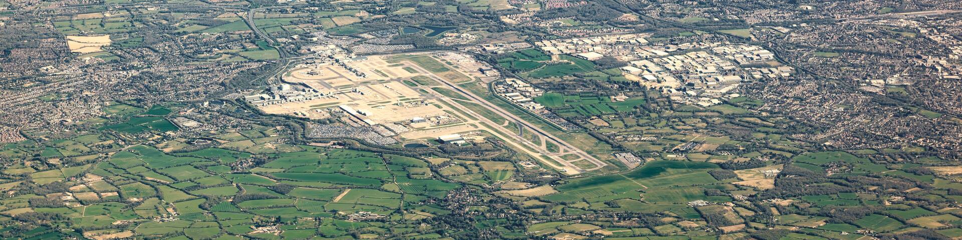 An aerial view of a rural landscape with fields, a small town, and a large open area with buildings.