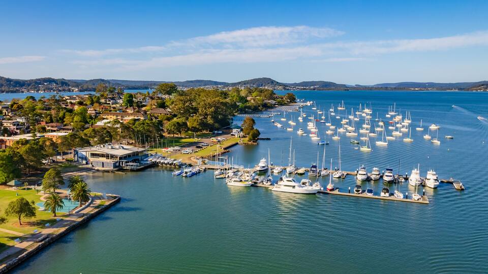 A marina with numerous boats docked, surrounded by residential buildings and greenery.