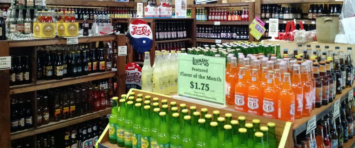 A store with shelves of beverages, a sign for Lehmans featured flavor, and a soda pop shop sign.